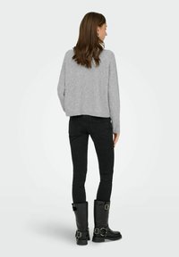 Grå cropped sweater, sorte skinny jeans og sorte knæhøje støvler med spænder. Blød tekstur og enkelt design med en afslappet pasform.