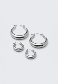 Štyri páry strieborných kruhových náušníc rôznych veľkostí: veľké hladké kruhy a menšie zaoblené štýly s lešteným povrchom a jednoduchými sponami.
