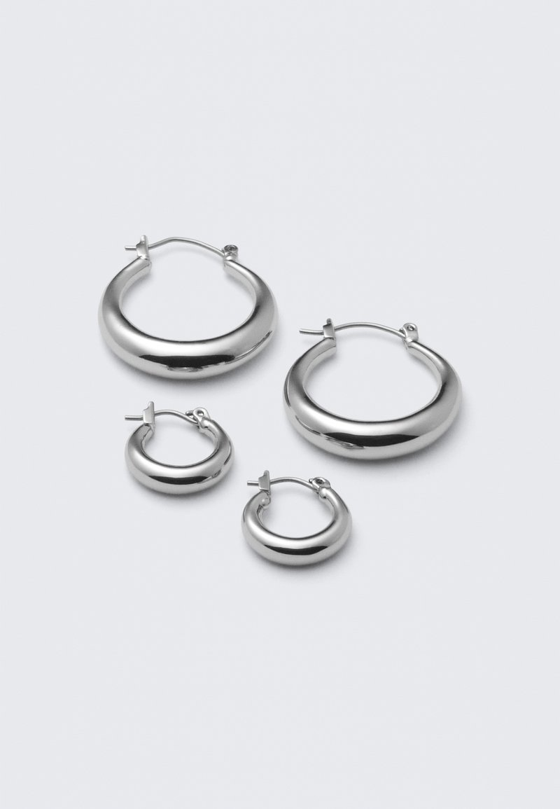 Štyri páry strieborných kruhových náušníc rôznych veľkostí: veľké hladké kruhy a menšie zaoblené štýly s lešteným povrchom a jednoduchými sponami.