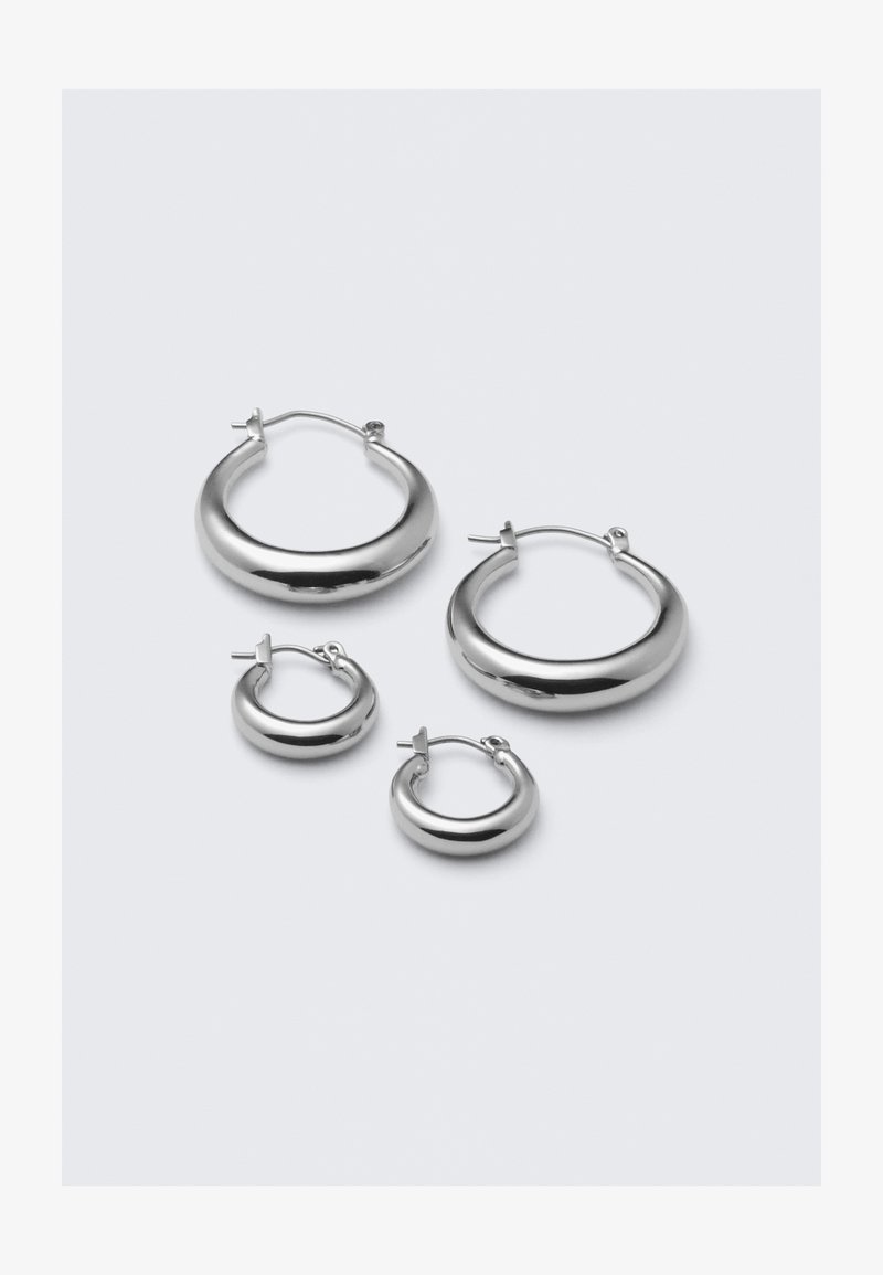 Štyri páry strieborných kruhových náušníc rôznych veľkostí: veľké hladké kruhy a menšie zaoblené štýly s lešteným povrchom a jednoduchými sponami.