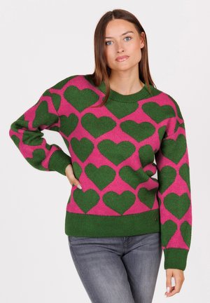 Gebreide sweater met een roze basis en groene hartpatronen, ribbelboord bij de ronde hals en mouwen. De stof lijkt zacht en textuur te hebben.