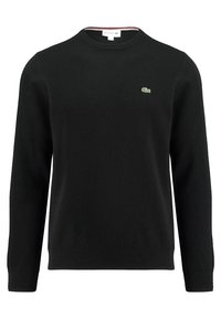 Svart stickad tröja med rund hals, prydd med en liten grön krokodil-logga på bröstet samt ribbade ärmslut och nederkant. Mjuk textur.