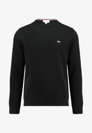 Maglione nero lavorato a maglia con collo rotondo, dotato di un piccolo logo di coccodrillo verde sul petto e polsini e orlo a costine. Texture morbida.