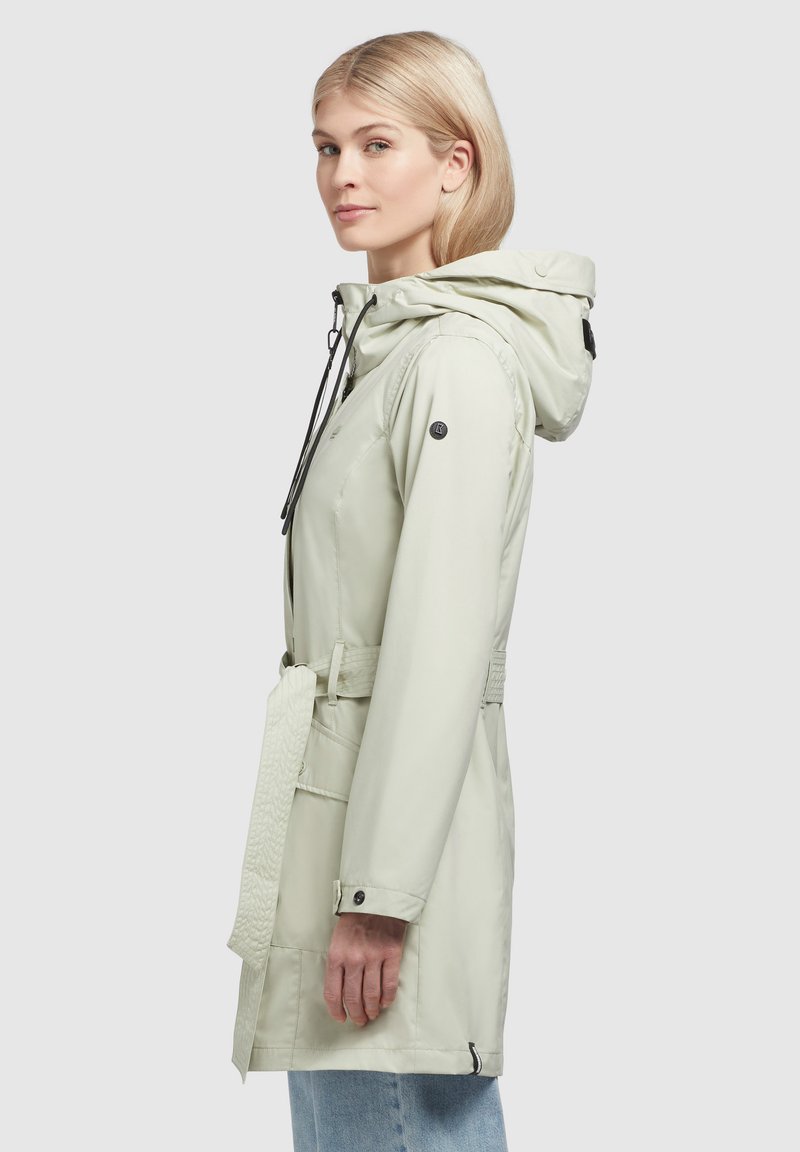 Giacca beige chiaro con cappuccio, cordino regolabile, vita con cintura e un accento testurizzato sulla cintura. Materiale impermeabile con bottoni a pressione.