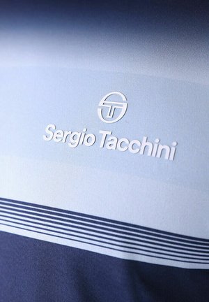 Sergio Tacchini-logo en merknaam op lichtblauwe stof boven een donkerblauw gebied met dunne horizontale strepen.