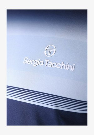 Sergio Tacchini-Logo und Markenname auf hellblauem Stoff über einem dunkelblauen Bereich mit dünnen horizontalen Streifen.