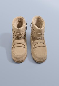 Tanfärgade mockastövlar med ett mjukt, plyschigt inre. Har en slouch-design, snörning framtill och en texturerad gummisula.