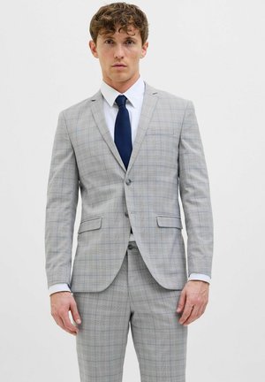 Light gray suit with a checked pattern featuring blue and yellow lines, single-button jacket, and matching trousers, worn with a white shirt and navy tie.