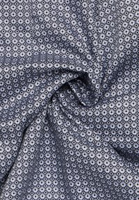 Geweven stof met een klein hexagonaal patroon in blauwe, grijze en witte tinten. De textuur lijkt glad en lichtgewicht.