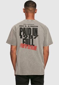 Grijze T-shirt met korte mouwen, voorzien van zwarte en rode tekst op de achterkant, die "Paid in Full" van Eric B. & Rakim promoot, met een vintage uitstraling.