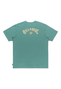 Camiseta de manga corta en color verde azulado con texto y logo beige "BILLABONG" centrados en la parte superior de la espalda.