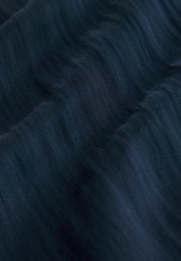 Marineblauwe stof met een zachte, gestructureerde oppervlakte met subtiele golfpatronen. Het materiaal lijkt lichtgewicht en licht reflecterend.