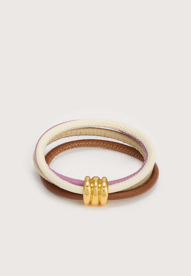 Τρία πλεκτά δερμάτινα βραχιόλια σε εκρού, ροζ και καφέ, με τρία μεταλλικά δαχτυλίδια σε χρυσό χρώμα ως διακόσμηση.