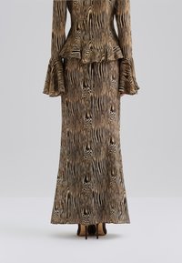 Larga vestido estampado en tonos marrones con rayas negras, que cuenta con una cintura de peplum acampanada y mangas de campana. Combinado con tacones oscuros.