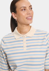 Polo beige avec des rayures bleues et brunes, doté d'un col classique et de quatre boutons au niveau du col. Matière en coton douce.
