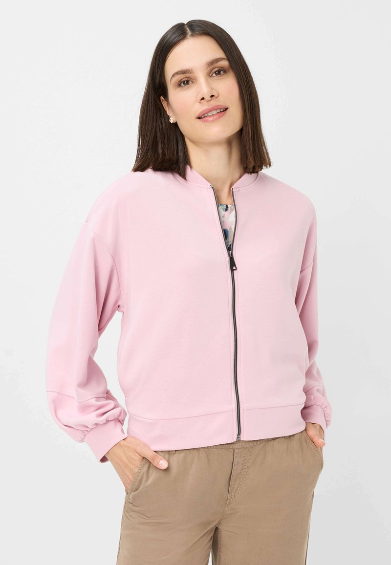 Lichtroze ritsjack met een hoge halslijn, drop shoulders en geribbelde manchetten. Glad materiaal met minimale details.