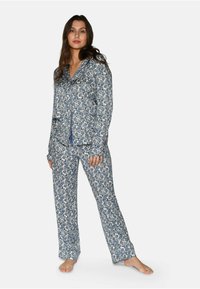Tvådelat pyjamasset i blått och vitt blommönster. Materialet är mjukt med en knäppningsskjorta och byxor med elastisk midja.