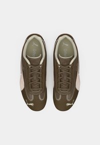 Zapatillas Puma en marrón y beige con cordones y detalles de costura, vistas desde arriba sobre un fondo blanco.