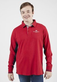 Polo à manches longues en coton rouge avec des panneaux latéraux et un col contrastants en marine, arborant un logo sur la poitrine.