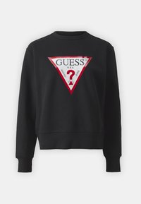 Sweat-shirt noir à manches longues avec un grand logo triangulaire Guess rouge et blanc comportant un point d'interrogation et le texte "U.S.A. Washed Jeans" à l'avant.