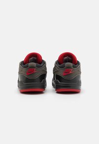 Le sneaker Nike nere e grigie presentano un colletto e una suola imbottiti rossi, con un logo distintivo sul tallone e dettagli testurizzati sulla parte superiore.
