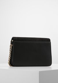 Borsa a tracolla in pelle nera e suede con catena, forma rettangolare, texture liscia e dettagli di cucitura sottili.