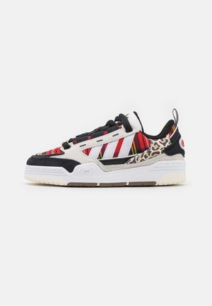 Bunte Sneakers mit gemischten Materialien, einschließlich rotem und schwarzem Stoff, Akzenten im Leopardenmuster und einer weißen Gummisohle mit strukturiertem Detail.