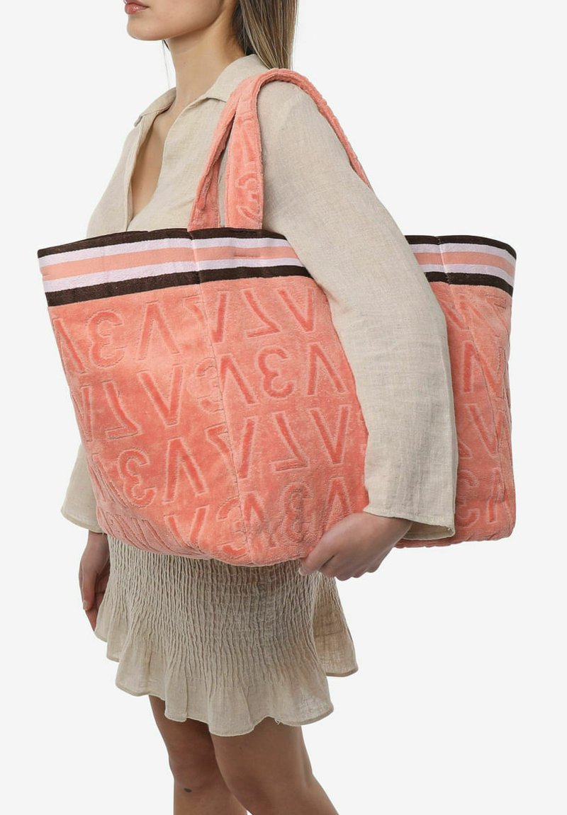 Große, korallfarbene Handtasche aus Frottee mit geprägtem Logo, gestreifter Oberteil in Pink und Braun, breite Griffe für einfachen Transport.
