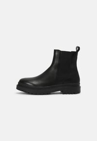 Botas Chelsea de cuero negro con paneles elásticos laterales, punta redondeada y una suela de goma gruesa con textura para mayor agarre.