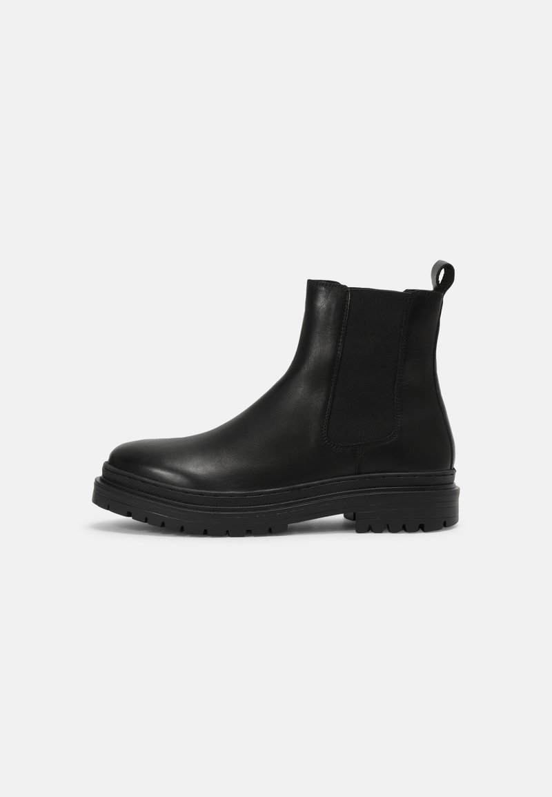 Botas Chelsea de cuero negro con paneles elásticos laterales, punta redondeada y una suela de goma gruesa con textura para mayor agarre.