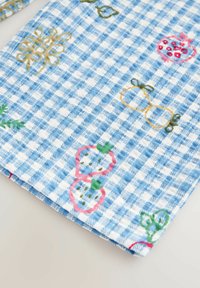 Tissu à carreaux bleu et blanc avec des fruits et légumes colorés brodés, dont des fraises, des citrouilles et des grenades.