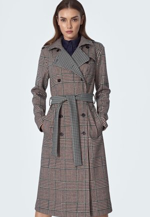 Beżowy, brązowy i zielony trencz w kratę z podwójnym zapięciem, szerokim kołnierzem, paskiem i dwiema przednimi kieszeniami. Tkanina o fakturze.