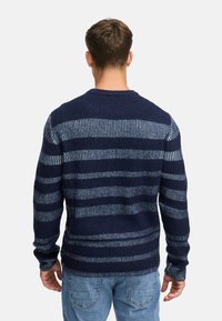 Marineblå og lyseblå stribet sweater med tekstureret strik, rund hals og lange ærmer. Båret over lyseblå jeans.