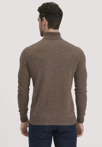 Brauner Pullover mit hohem Kragen, gestrickter Textur und taillierter Silhouette. Die Ärmel sind lang und haben gerippte Bündchen und einen gerippten Saum für eine enge Passform.