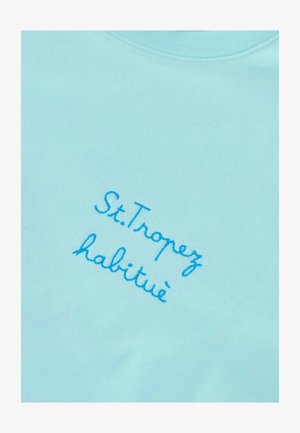 Pullover azzurro chiaro con testo ricamato; la scritta recita "St. Tropez habitué." Tessuto liscio, design con scollatura a girocollo.