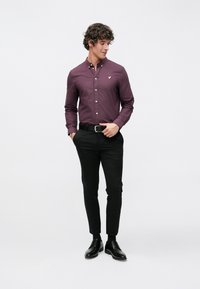 Bordó gombos pamut ing, slim fit, kis hímzett logóval a mellkason; fekete nadrággal és cipővel párosítva.