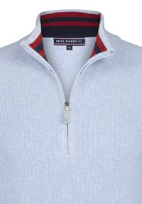 Vaaleansininen neulottu pusero, jossa on neljäsosa vetoketjulla, ja jossa on raidallinen laivastonsininen ja punainen kaulus. Brändin merkki ommeltu kaulan sisäpuolelle.