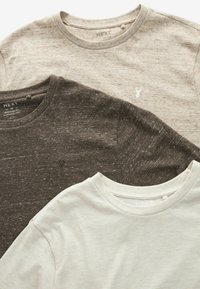 Tre crew-neck t-shirts i beige, mørkebrune og kremfarvede. Blødt, struktureret stof med et subtilt meleret mønster og lille logo detalje.