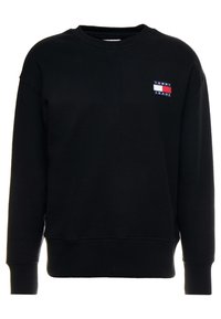 Felpa nera in cotone, con scollatura tonda, maniche lunghe, polsini a costine e un logo Tommy Jeans in rosso, bianco e blu sul petto.