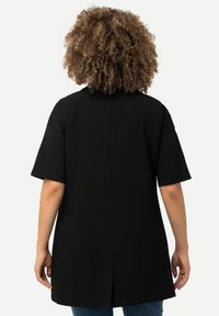 Svart kortärmad skjorta med rak passform, med en mitterseam och detalj med slits bak. Mjukt tyg med en slät textur.