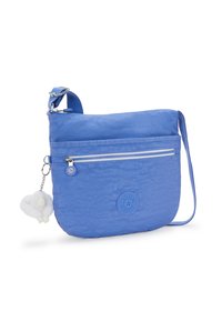 Modrá nylonová crossbody taška s hladkým povrchem, obsahující zipovou přední kapsu, nastavitelný popruh a připevněný nadýchaný přívěsek.