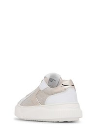 Beige and white sneaker with a mesh upper, metallic accents, and a textured rubber sole. Features a rounded shape and slip-on design.