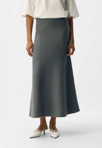 Gray, wool-blend midi skirt with a straight silhouette, featuring a smooth texture and a high waistband, paired with white, pointed-toe mules.