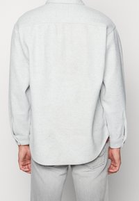 Grå flannel skjorte med knap-ned krave, lange ærmer, sideslids og en afslappet pasform. Blød tekstur med en ensartet farve.