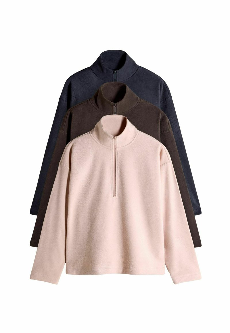 Trois pulls en polaire de couleur rose clair, marron foncé et marine. Chacun est doté d'un col montant et d'une fermeture éclair à l'avant, avec un matériau doux et texturé.
