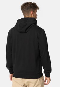 Fekete kapucnis pulóver laza szabással, állítható húzózsinóros kapucnival, bordázott mandzsettákkal és szegéllyel. Puha anyag, nem látható logók vagy minták.