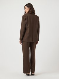 Fato castanho sob medida com um blazer estruturado e calças de perna larga, feito de um tecido suave e com detalhes de costura discretos.