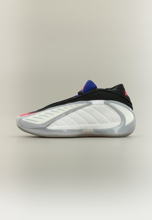 Vue latérale d'une chaussure de sport moderne avec des panneaux blancs, noirs, gris et bleus, présentant une semelle texturée et un design élégant.