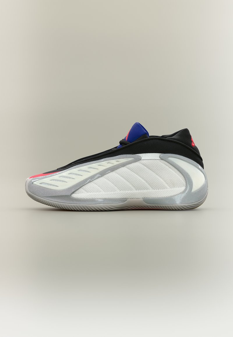 Πλάγια όψη ενός μοντέρνου αθλητικού παπουτσιού με πάνελ σε λευκό, μαύρο, γκρι και μπλε χρώμα, που διαθέτει υφή στη σόλα και κομψό σχεδιασμό.