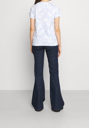 Lichtblauw tie-dye T-shirt met korte mouwen, gecombineerd met donkerblauwe wijde jeans. De outfit heeft een losse pasvorm en een casual ontwerp.